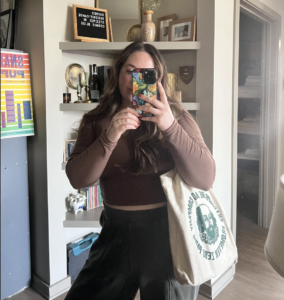 image of a girl taking her picture in the reflection of a mirror with a tote bag on her shoulder